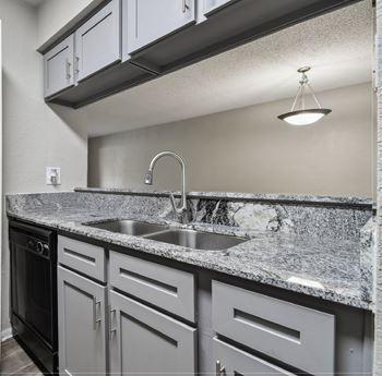a kitchen with white cabinets and granite counter tops and a sink